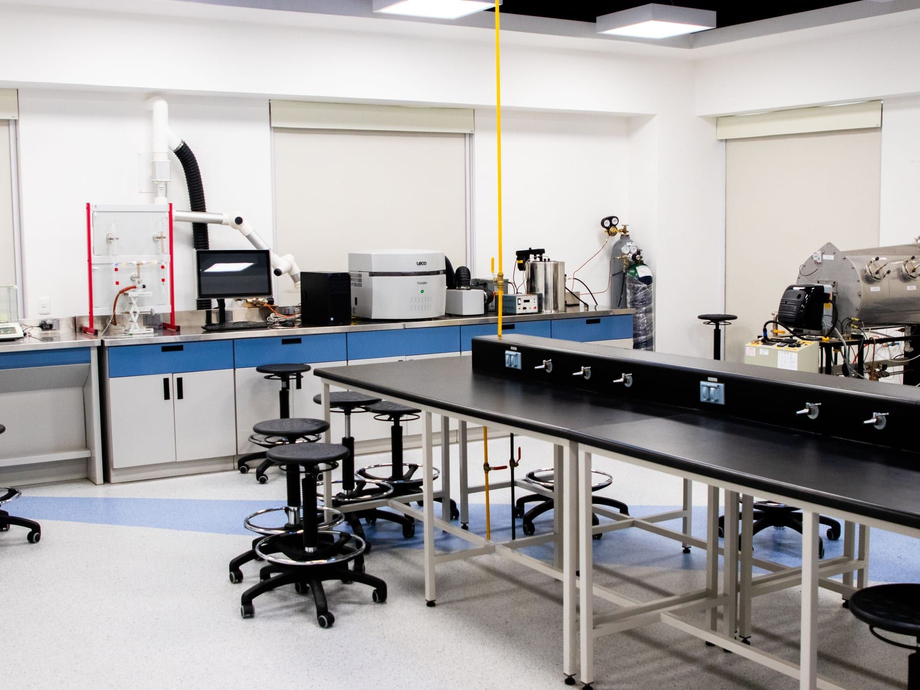 A newly fitted lab: open benches, stools, gas lines and a few instruments along the wall.